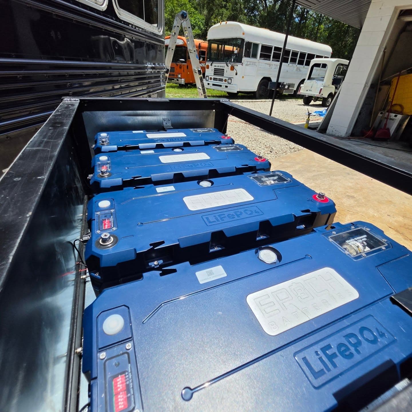 Four Epoch LiFePO4 batteries on the slide-out battery tray of a converted coach bus