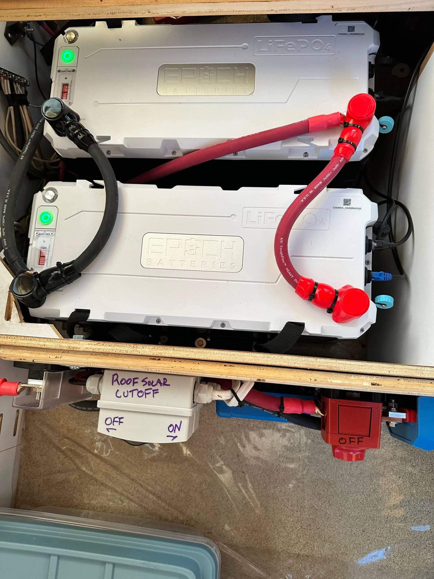 Two Epoch 12V 460Ah LiFePO4 batteries cabled with 4/0 wire in an RV battery bay above a roof solar cutoff switch