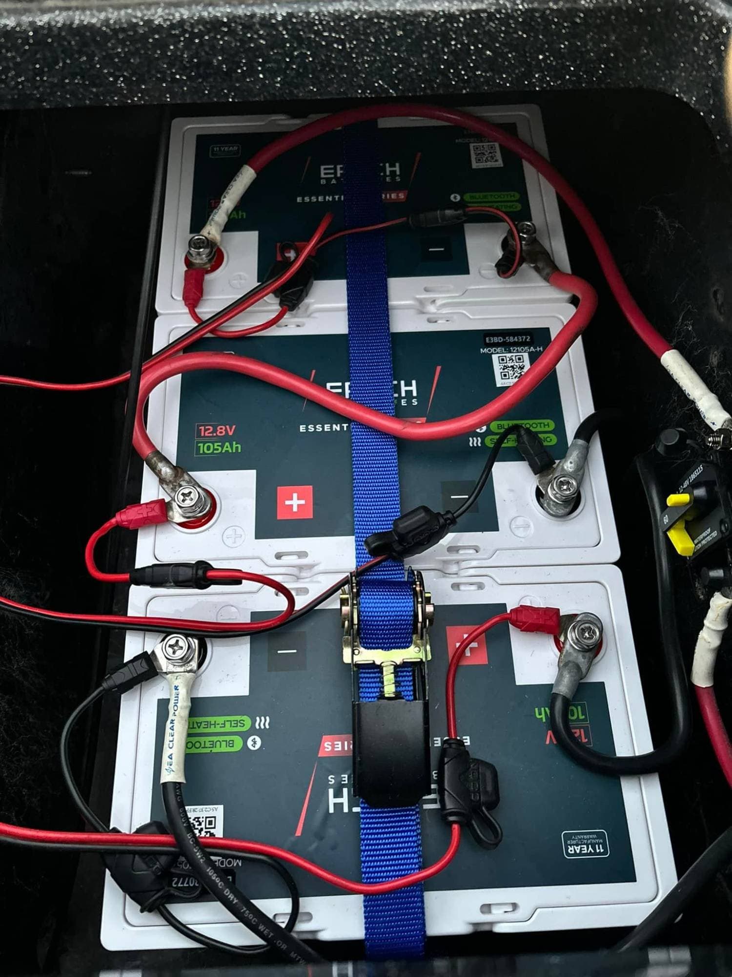Three Epoch Essential Series 12V 105Ah heated Bluetooth LiFePO4 batteries strapped into a boat's battery compartment