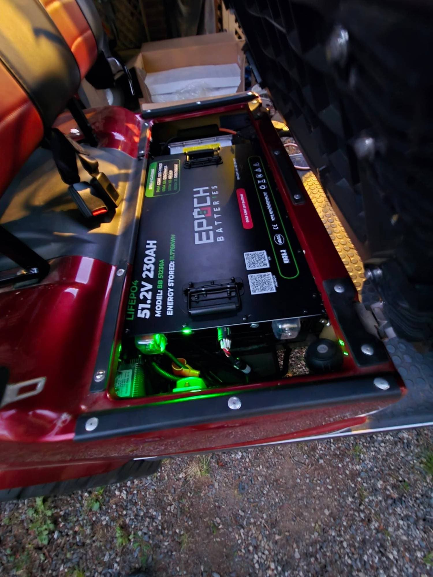 Epoch Big Box 48V 230Ah LiFePO4 golf cart battery under the seat of a red golf cart, its status lights glowing green